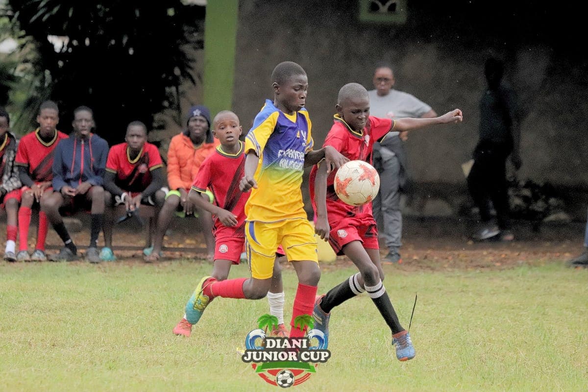 A young footballer carrying the ball during Diani Junior Cup action.