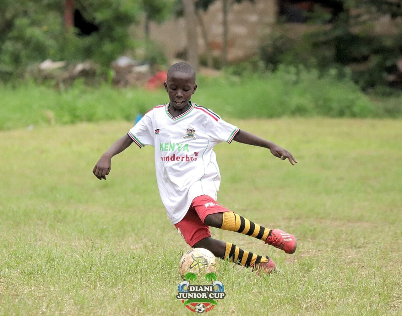 A young footballer preparing to pass the ball on the DJC pitch.