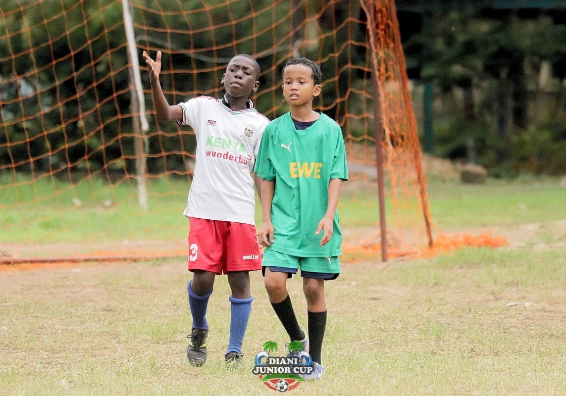 Two youth players greeting one another beside the DJC goal.