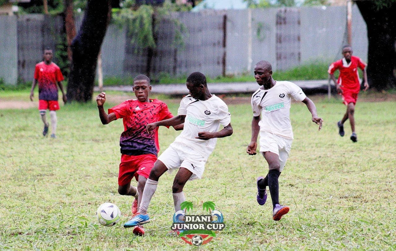 Youth footballers moving the ball during a competitive DJC match.