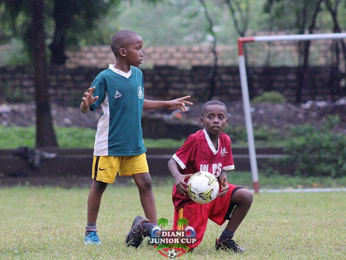 Young footballers sharing the pitch during a Diani Junior Cup match.